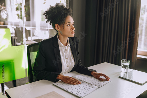 Visually impaired office worker seated at the table using Braille