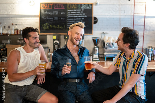 LGBTQ Friends sit at a bar with beer and champagne