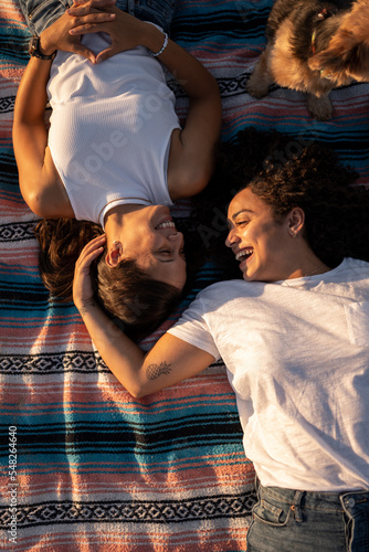 Hispanic lesbian couple lie on blanket at the beach