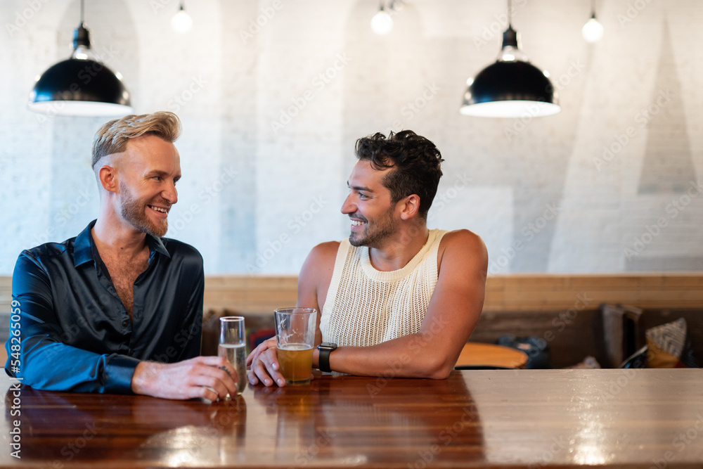 LGBTQ Friends sit at a bar with beer and champagne LGBTQ Friends sit at a bar with beer and champagne