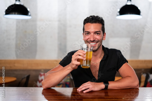 Gay man sits at a bar with beer