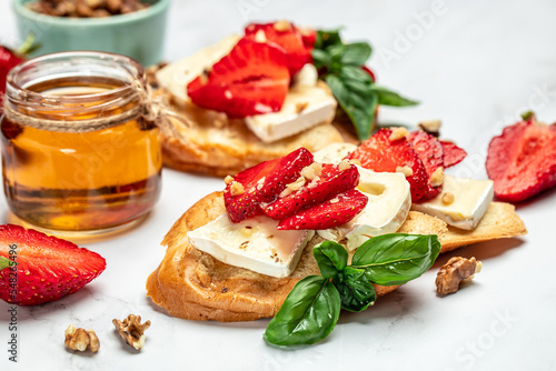 Bruschetta with strawberries, cheese camembert nuts and honey on a light background. banner, menu, recipe place for text, top view