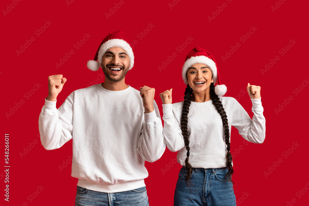 Portrait Of Overjoyed Arab Couple Wearing Santa Hats Celebrating Success Together Portrait Of Overjoyed Arab Couple Wearing Santa Hats Celebrating Success Together