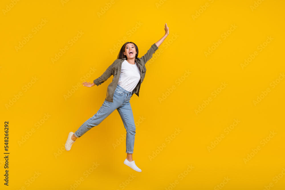 Full body size photo of young crazy japanese addicted shopaholic lady jumping air raise arm up empty space isolated on yellow color background