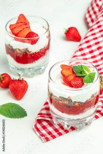 Two Glass of parfait with fresh fruit  yogurt and granola on white table. vertical image. top view. place for text