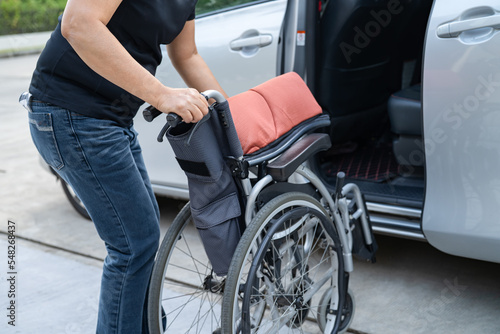Asian woman folding and lift up wheelchair into her car. Accessibility concept.