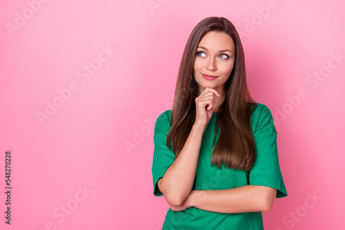 Portrait of gorgeous optimistic thoughtful girl wear green t-shirt hand on chin look empty space isolated on pink color background