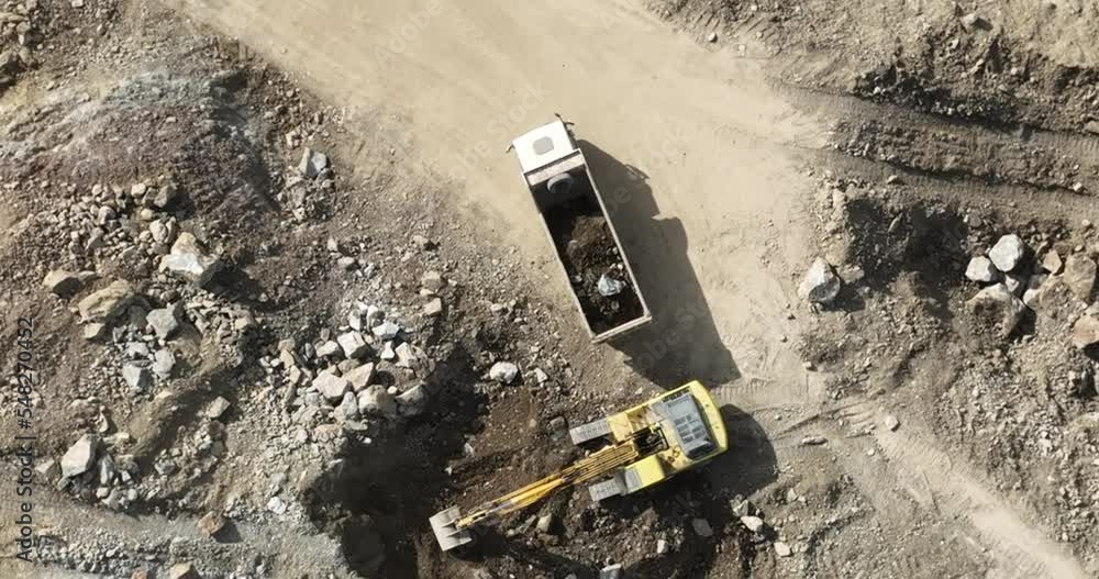Industrial mine excavators are digging the soil in the construction site and loading trucks. Aerial drone top view. Industrial mine excavators are digging the soil in the construction site and loading trucks. Aerial drone top view.
