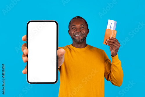Positive black man showing passport, tickets and smartphone, mockup