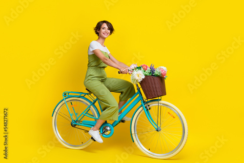 Full body photo of gorgeous young lady riding bicycle feminine movement wear trendy khaki clothes isolated on yellow color background