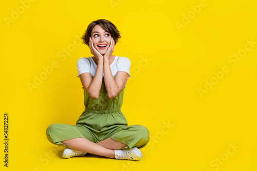 Full body photo of nice young girl touch cheeks look empty space impressed wear trendy khaki clothes isolated on yellow color background