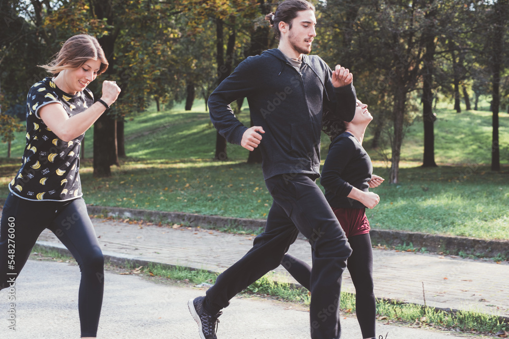 Obraz premium Three runners sprinting outdoors training in a park area together