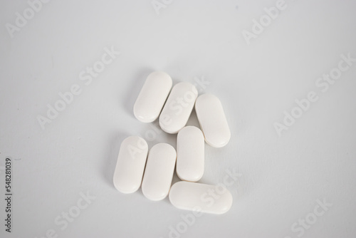 White pills on white background close up top view 