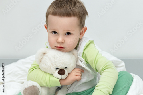 portrait of a child 3 years old in clothes for sleep, hugging a teddy bear, bedtime, daily routine
