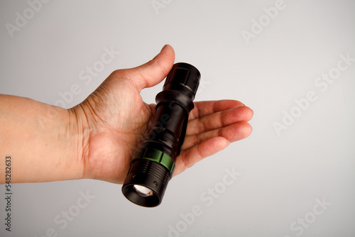 Pocket flashlight.The girl holds it in her hand.To illuminate the environment while hiking. LED spotlight.flashing lamp light.Flash. close-up.On a white isolated background.(EDC). 