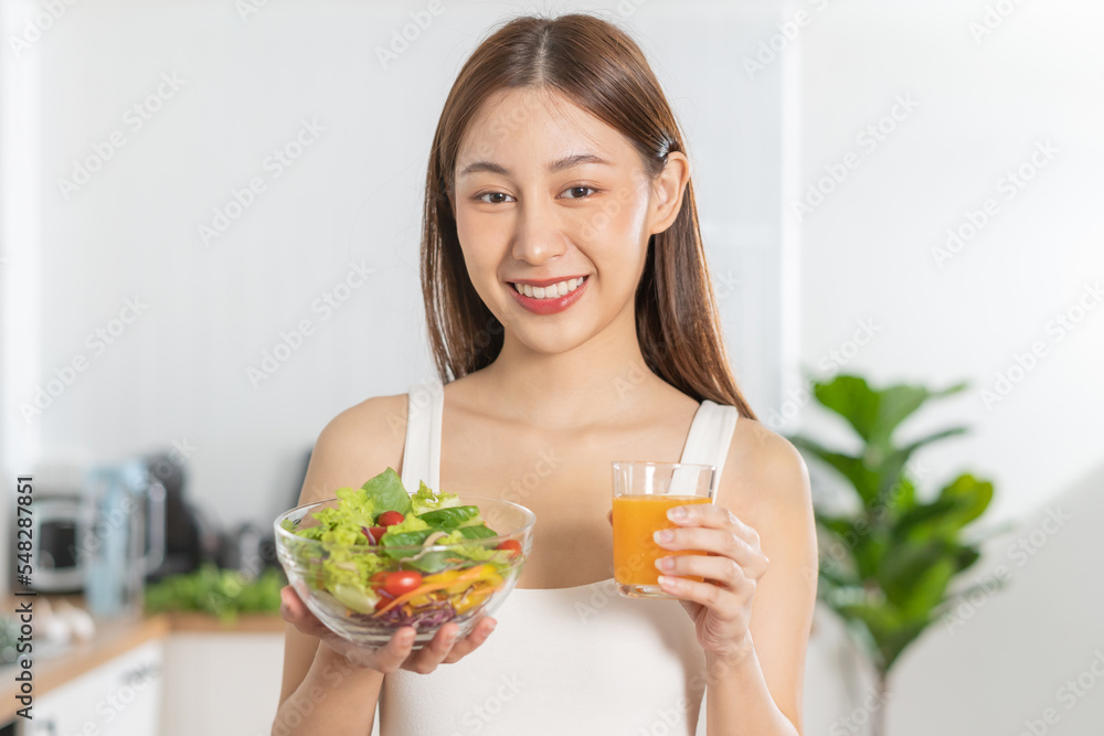Diet, Dieting, pretty asian young woman or girl smiling, holding glass of orange juice and mix vegetables, green salad bowl. eat food is low fat good healthy. Nutritionist weight loss health person. Diet, Dieting, pretty asian young woman or girl smiling, holding glass of orange juice and mix vegetables, green salad bowl. eat food is low fat good healthy. Nutritionist weight loss health person.
