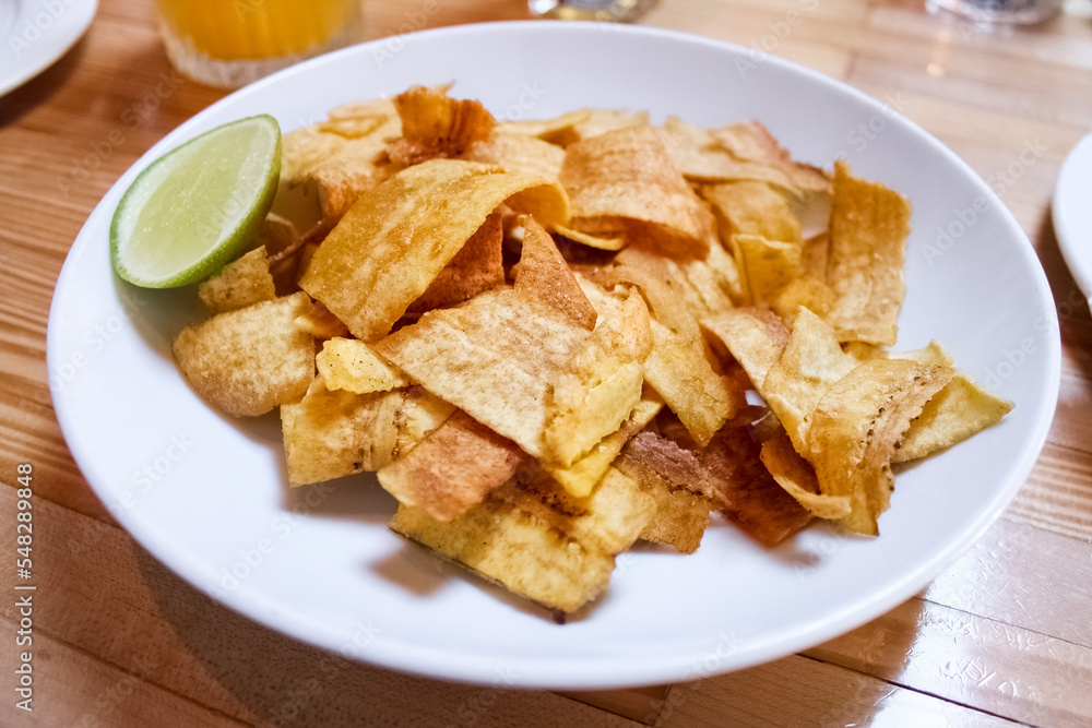 A plate of fried, crispy banana chips and a slice of lime. Baked sliced bananas. Close-up A plate of fried, crispy banana chips and a slice of lime. Baked sliced bananas. Close-up