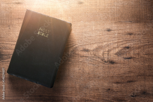 Bible on a wooden table, the flash of light is on the bible, copyspace, flat lay