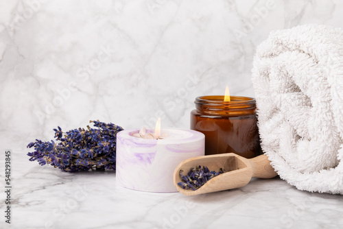 Lavender flowers and scented candle. The concept of spa  beauty and health salon  skin care cosmetics. Natural cosmetics.Aroma procedures. Closeup on white marble background.