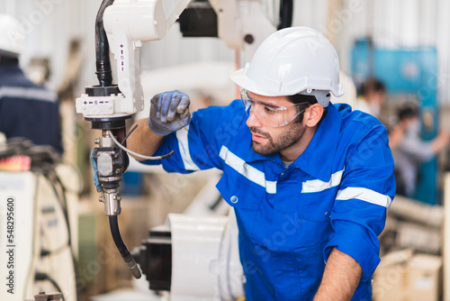 Caucasian man specialist engineer in uniform checking a robotic arm in factory warehouse, Testing new innovation automation robot for industrial. 