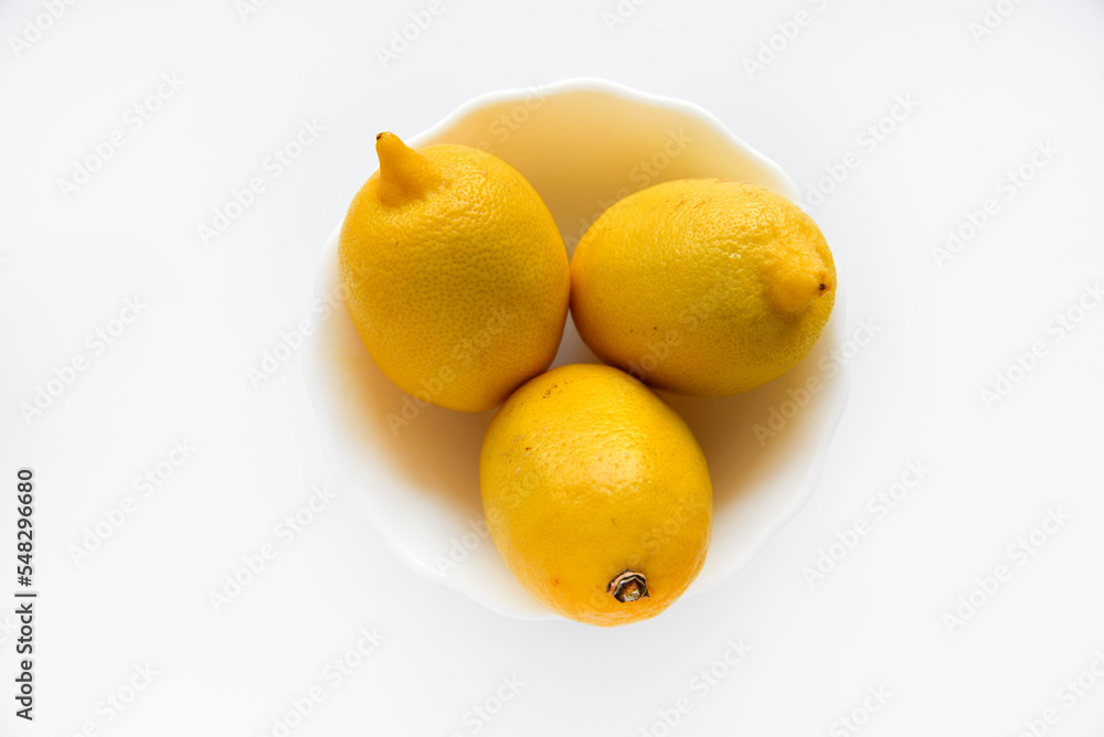 Yellow juicy lemons in a white saucer. Delicious yellow lemons on a white background. Beautiful lemons on a plate. Yellow juicy lemons in a white saucer. Delicious yellow lemons on a white background. Beautiful lemons on a plate.