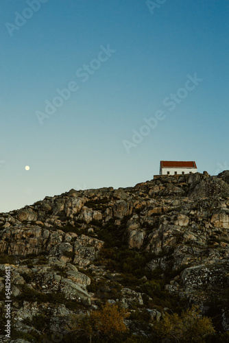 small house on the top of the rock, sky with moon, mountains