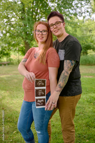 Same sex female couple holding ultrasound of unborn baby.