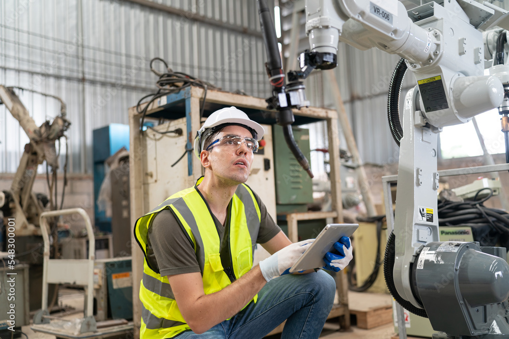Robotics engineer working on maintenance of modern robotic arm in factory warehouse Robotics engineer working on maintenance of modern robotic arm in factory warehouse