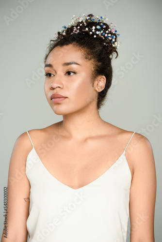 young african american woman with blooming gypsophila flowers in hair isolated on grey.