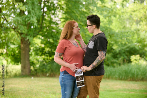 Same sex female couple holding ultrasound of unborn baby.