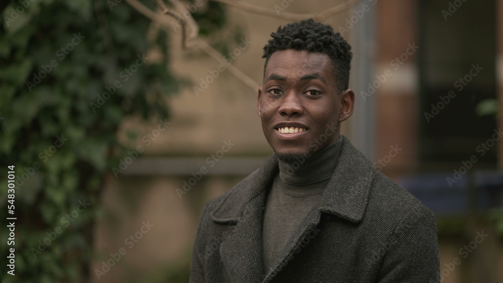 Smiling happy black African man standing outdoors during winter season Smiling happy black African man standing outdoors during winter season