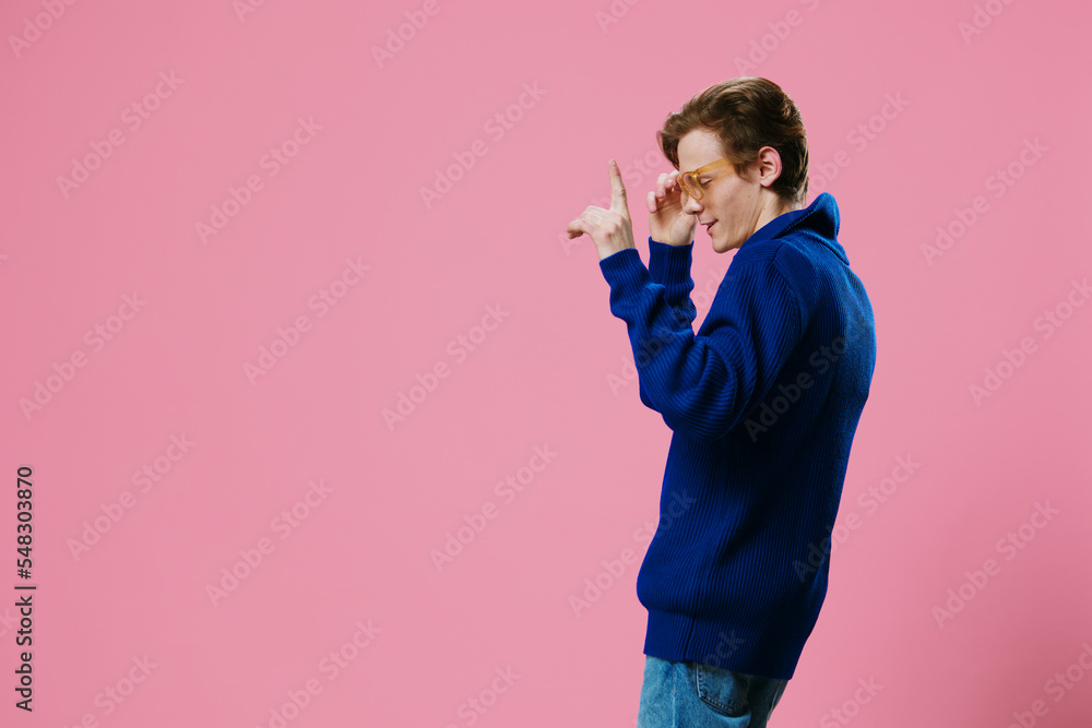 a joyful, happy, funny guy stands on a pink background dancing happily in orange glasses and a blue autumn zipper sweater. test space a joyful, happy, funny guy stands on a pink background dancing happily in orange glasses and a blue autumn zipper sweater. test space