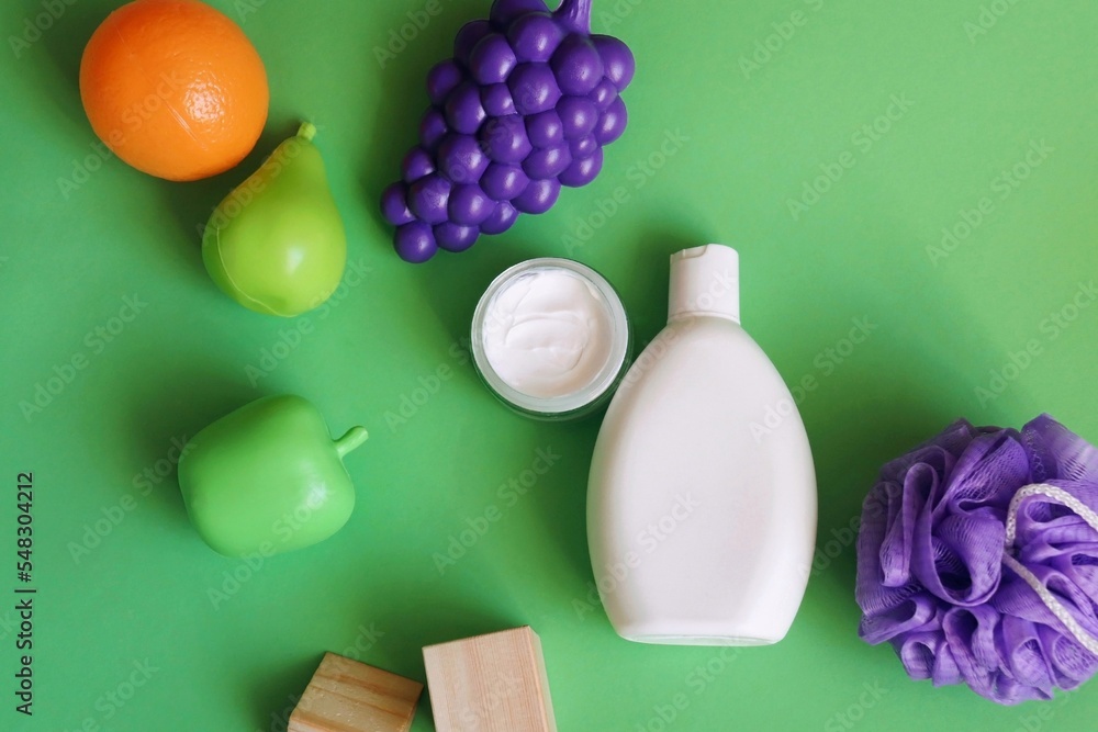 White shampoo bottle, moisturizing face cream and fruits on a green background. Flat lay beauty photo. Organic cosmetic products for hair and skin care White shampoo bottle, moisturizing face cream and fruits on a green background. Flat lay beauty photo. Organic cosmetic products for hair and skin care