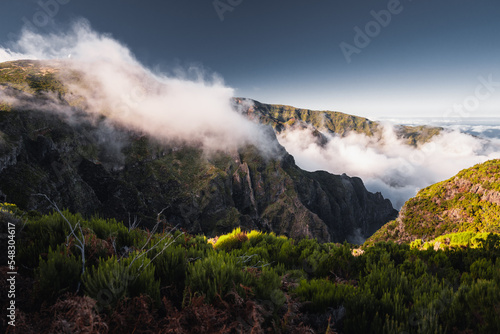 Amazing scenic view from a madeira trip at amazing sunsetlight in the mountsina with a view down to the sea in a moody and foggy but also bright weather.