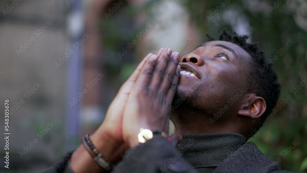Religious young black man praying to God. African person looking up at sky with HOPE and FAITH