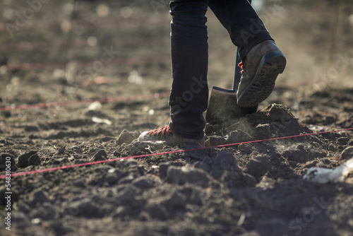 Details with a person shovelling dry, arid and dusty soil during a planting activity.