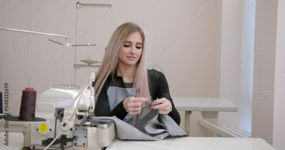 Female tailor cutting fabric sitting at sewing machine Female tailor cutting fabric sitting at sewing machine