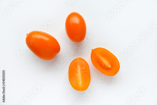 Whole and sliced yellow tomatoes on a white background. Delicious and juicy yellow tomatoes.  Tomato fruits in a group close-up.