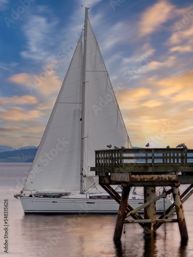 Sailboat sails past the fishing pier during sunrise in Sidney BC © pr2is
