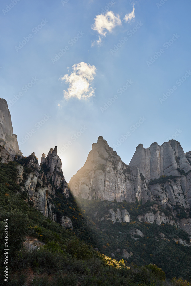 rays of light crossing the mountains in montserrat at sunset with some autumn colors