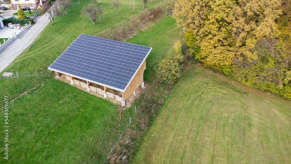 Solar panels are installed on the roof of a village farm building