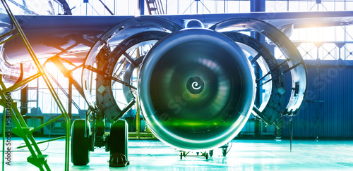 Repair maintenance of aircraft engine open hood on the wing of the plane. Industrial theme view in blue-green hue with bright sources of warm light. Format banner header wide size, place sample text.
