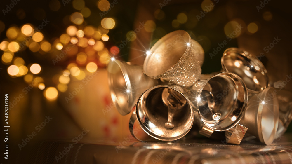 Gold and silver christmas bells with heart lights in front of christmas
