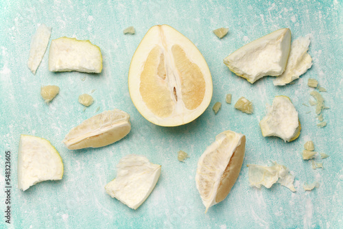 Close up ripe juicy fresh cut sliced yellow Pomelo on mint blue color cement background. Shaddock, citrus maxima, tropical fruit. Top view. Flat lay. 