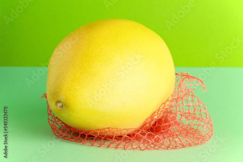Close up ripe juicy fresh whole yellow Pomelo on green color background. Shaddock, citrus maxima, tropical fruit. 