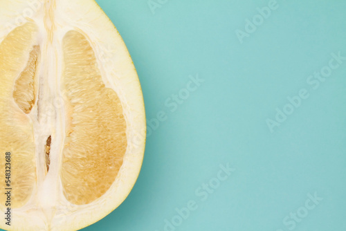 Close up ripe juicy fresh cut sliced yellow Pomelo on mint blue color background. Shaddock, citrus maxima, tropical fruit. Top view. Flat lay. Space for text. Copy space