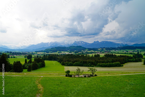 the lush green alpine meadows of the scenic Rueckholz district in the Bavarian Alps in Ostallgaeu  Bavaria  Germany on a rainy summer day with heavy dark clouds