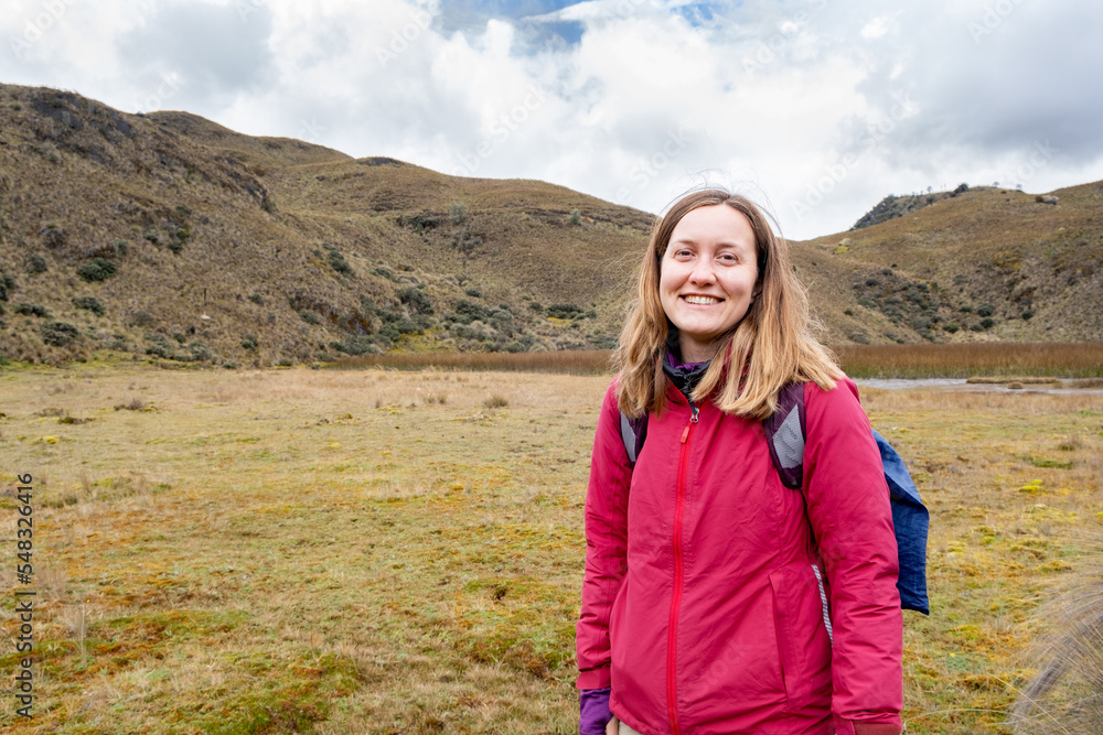 A happy female hiker looking at camera in the Cajas National Park in the highlands of Ecuador, tropical Andes.