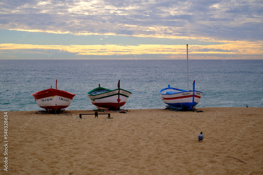 small coloured wooden fishing boats, in front of the mediterranean beach, about to go fishing by the fishermen, on the calm mediterranean beach