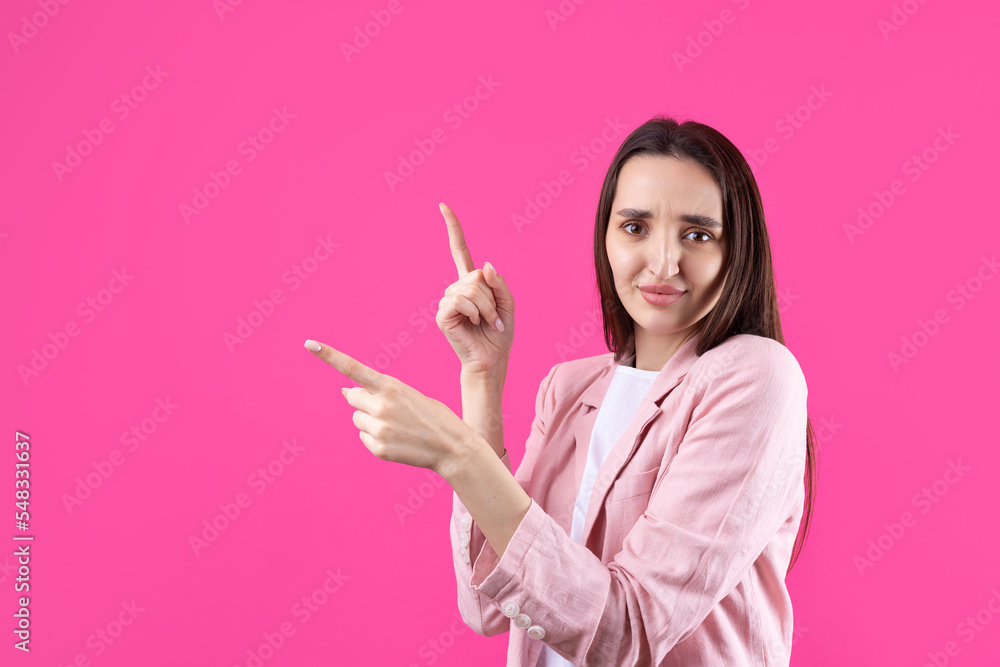 Happy young caucasian female in a pink jacket pointing fingers away Happy young caucasian female in a pink jacket pointing fingers away